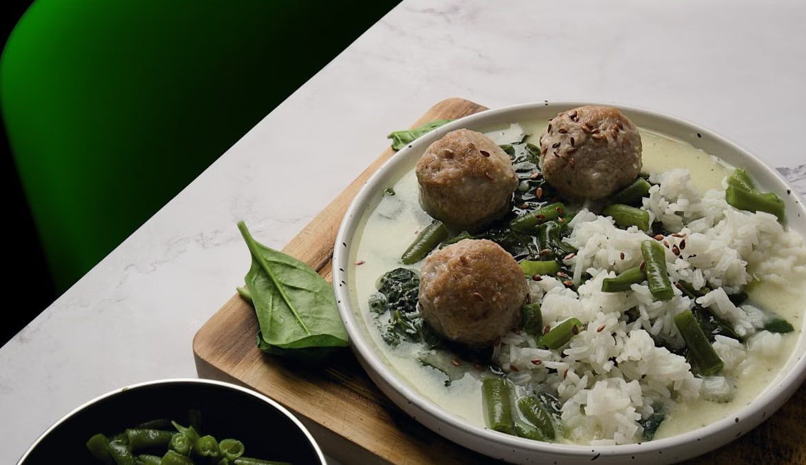 A savory dish of meatballs, rice, and green beans on a decorative plate.